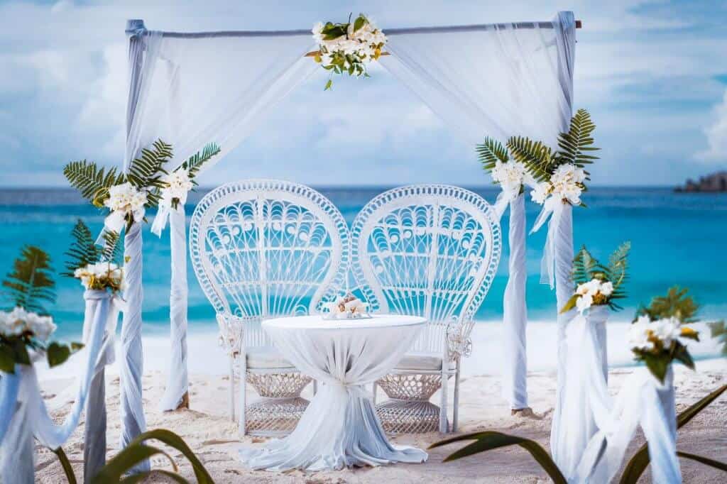 Beach wedding arch gazebo ceremonial decorated with white flowers on a tropical grand anse sand