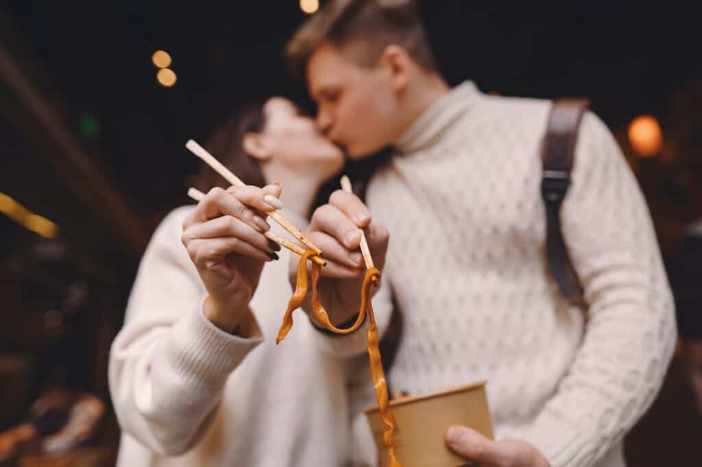 newlywed couple eating noodles with chopsticks in Shanghai outside a food market