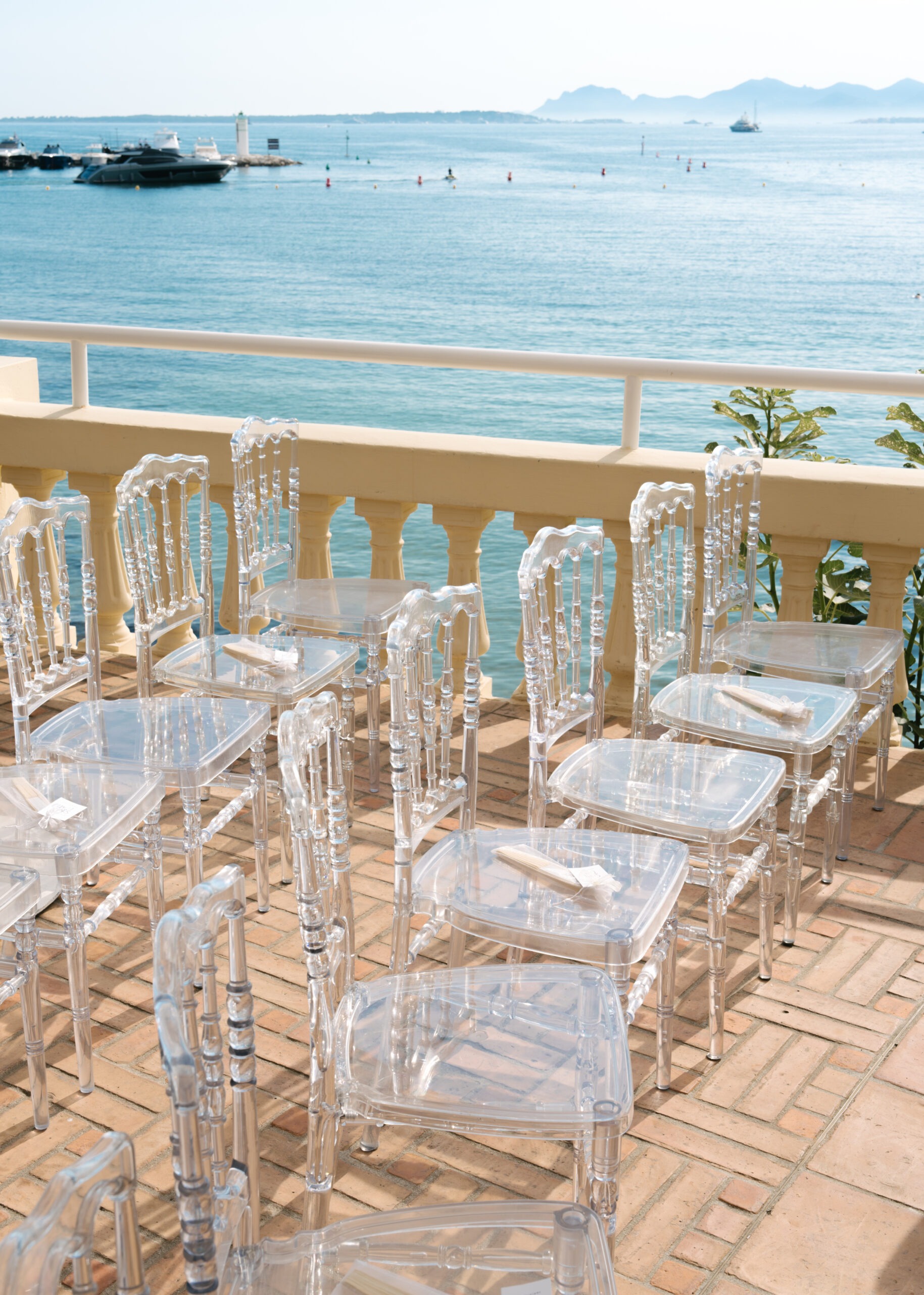 Transparent ceremony chairs arranged beside the sea at Hôtel Belles Rives.