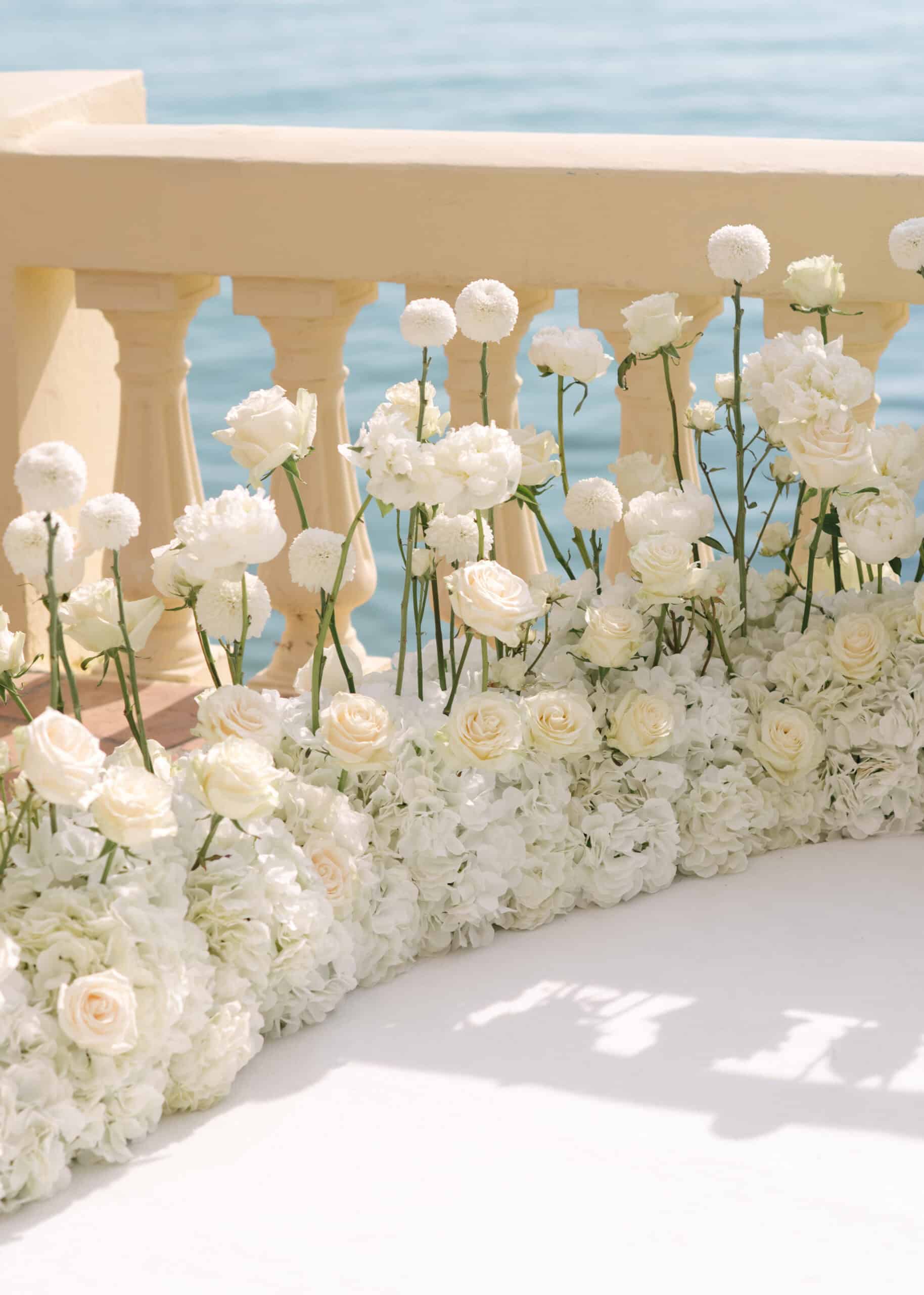Sculptural white rose and hydrangea installation beside a seafront balustrade at Hôtel Belles Rives.