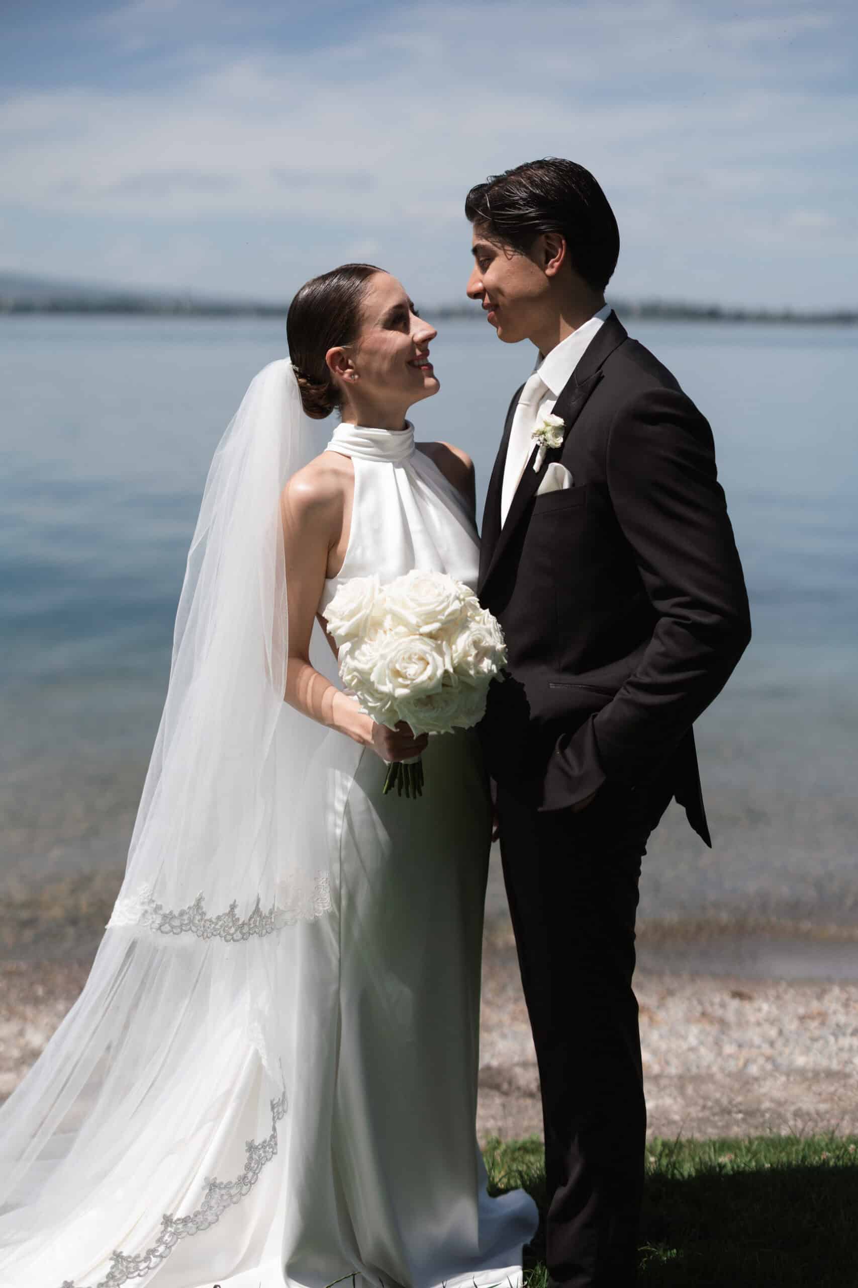 Francesca and Giuseppe standing beside the water with a white bridal bouquet.