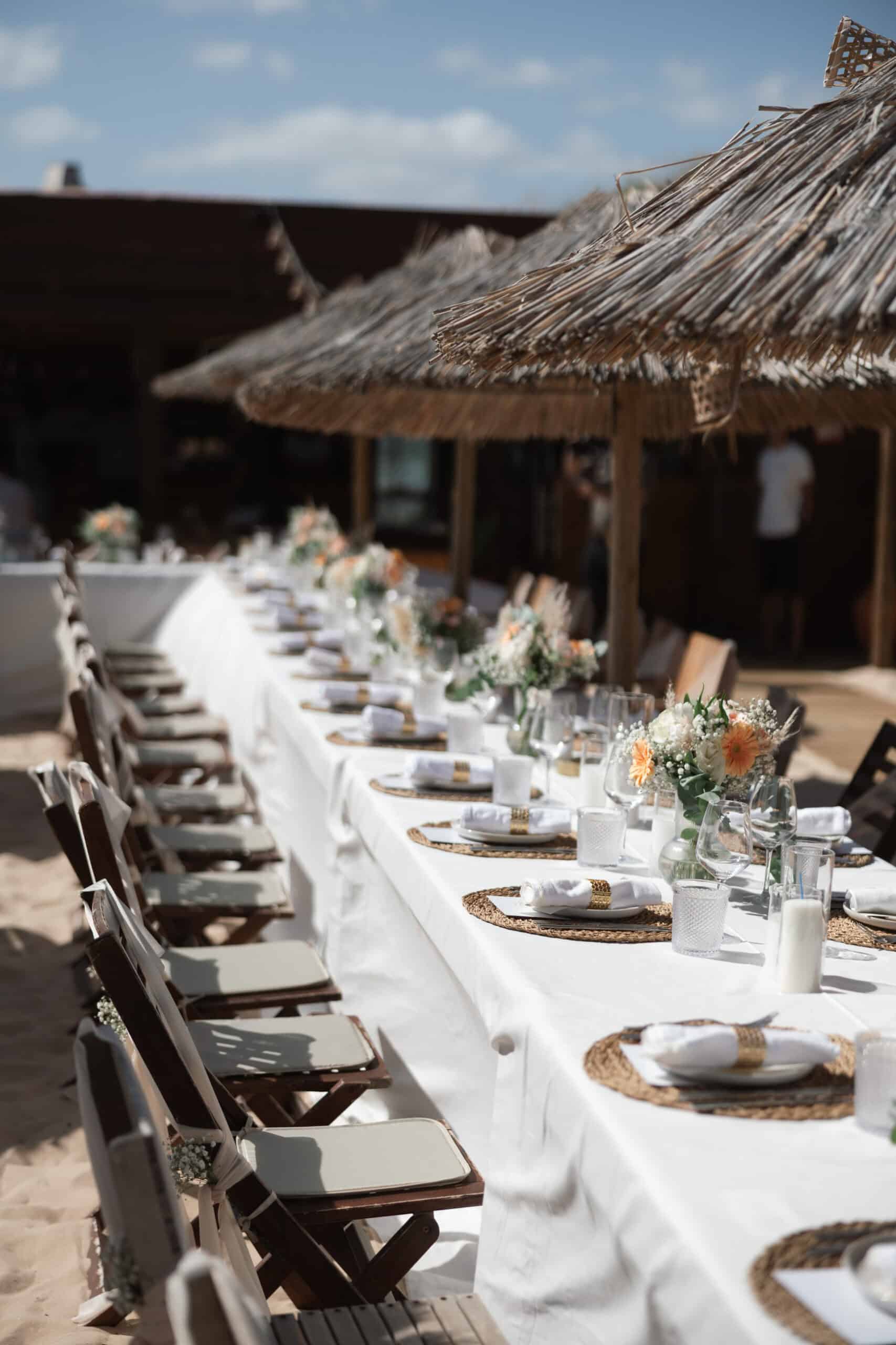 Long reception table at Lily and Michael’s wedding with woven placemats, white linen and peach flowers.