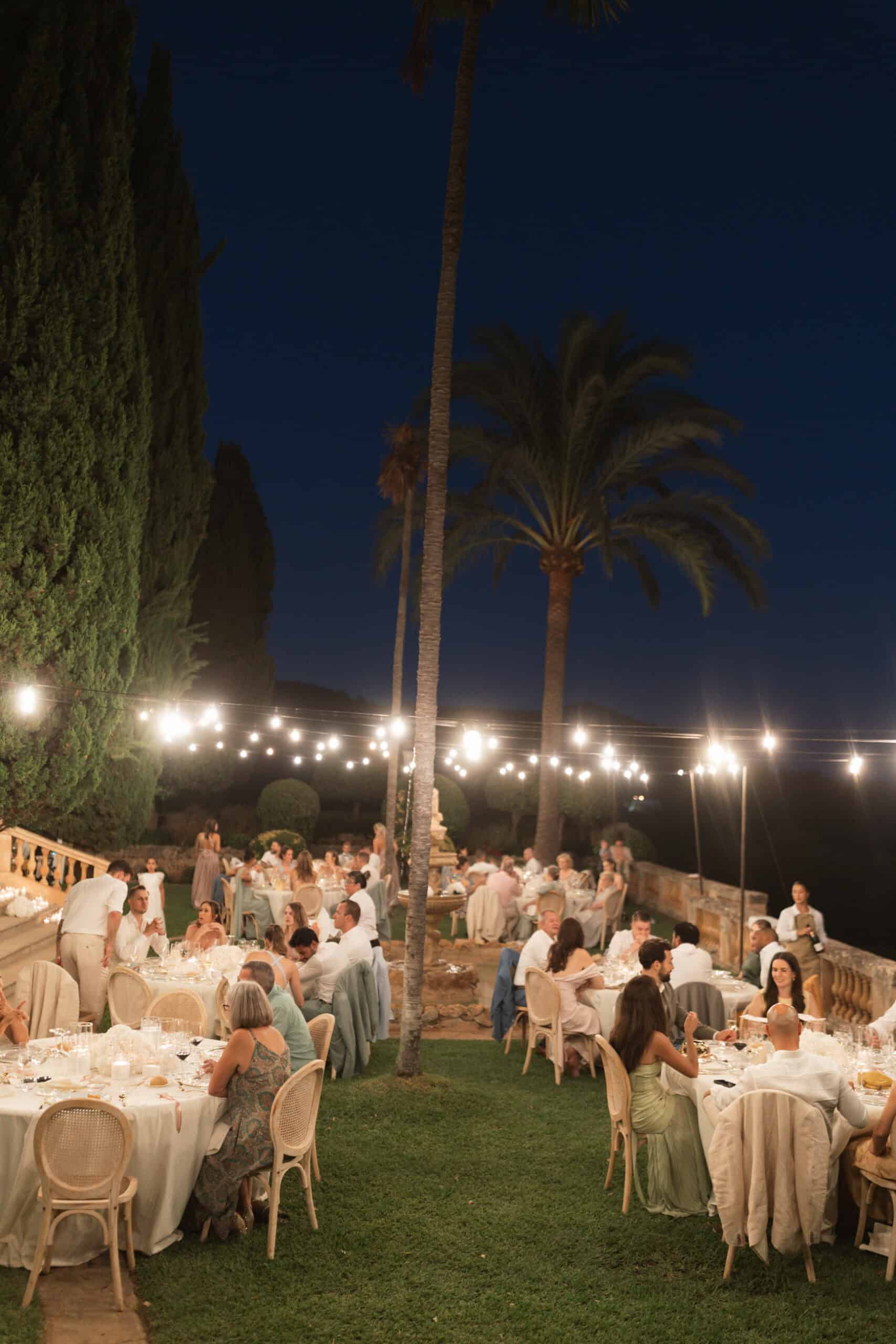 Guests at Yaiza and Stefan’s outdoor wedding dinner at Son Togores beneath strings of lights.