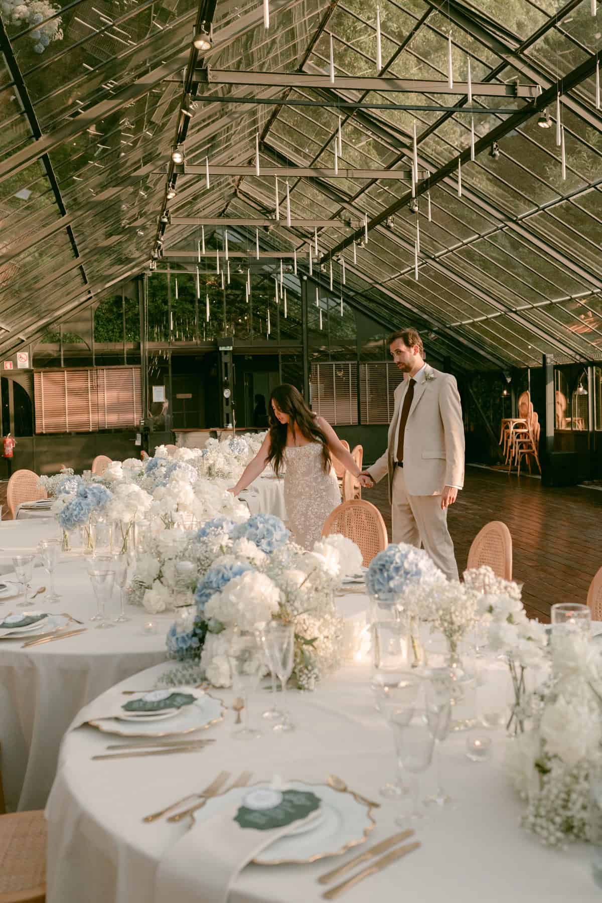 Jacqueline and Andrew beside their wedding reception tables beneath the glass roof.