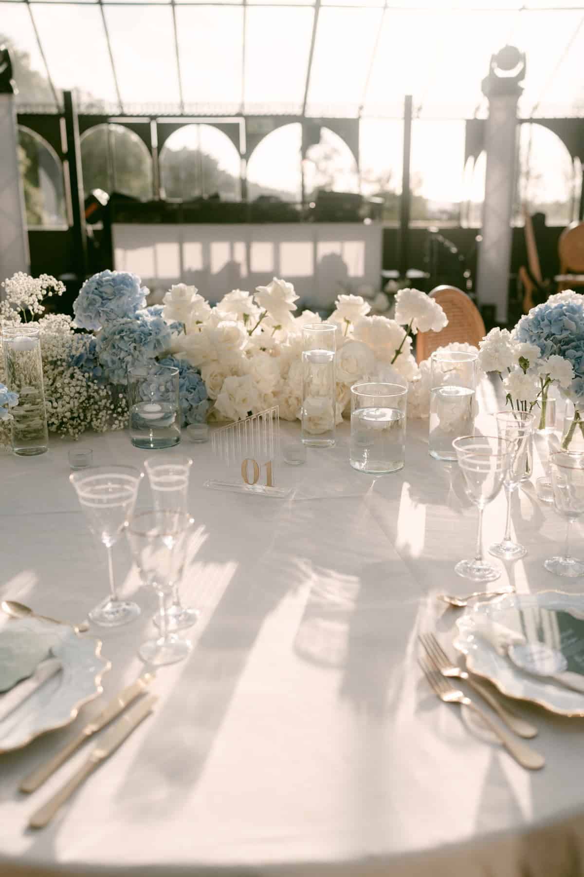 Glassware and white and pale blue flowers on a wedding reception table at Quinta da Bella Vista.